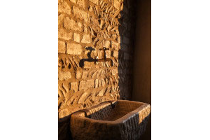 Sunset light on an original wall made with rest of roof tiles. An antique pigs trough for sink