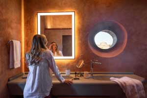 Close up shot of the solid <i>pietra serena</i> carved stone sink and double lit mirror