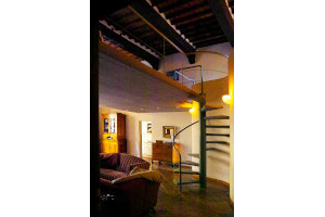 The Benci double height residence. A minimal spiral staircase connects the groundfloor livingroom wiht the upper bedroom (on a partial mezzanine)…